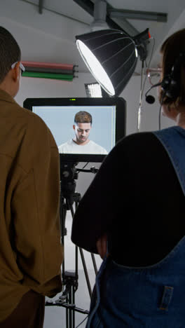 Vertical-Video-Of-Female-Film-Director-And-Assistant-Watching-Performance-Of-Actor-On-Monitor-Shooting-Movie-In-Studio-Shot-In-Real-Time